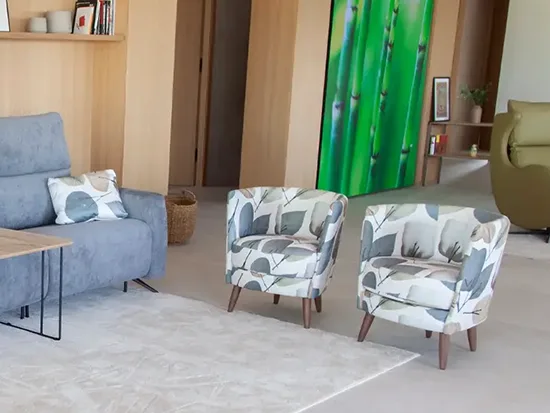 Fauteuil pivotant Fama Peque en tissu clair, présenté avec un canapé dans un séjour – Meubles Bouchiquet à Bergues (59)