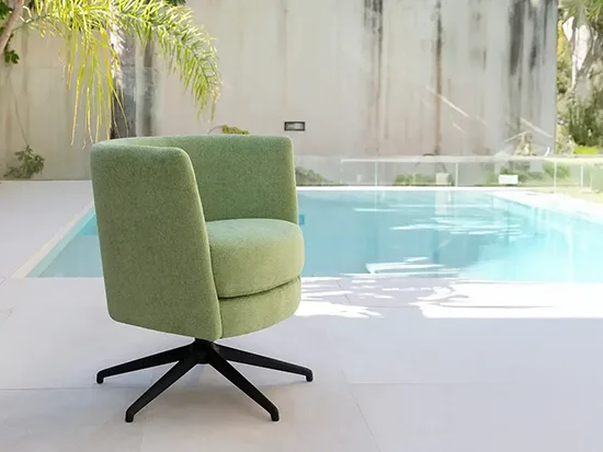 Fauteuil pivotant Fama Peque en tissu vert, présenté près d’une piscine – Meubles Bouchiquet à Bergues (59)