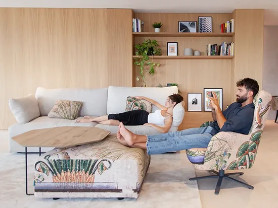 Fauteuil en tissu Fama Kylian avec une personne assise, présenté dans un salon – Meubles Bouchiquet à Bergues (59)