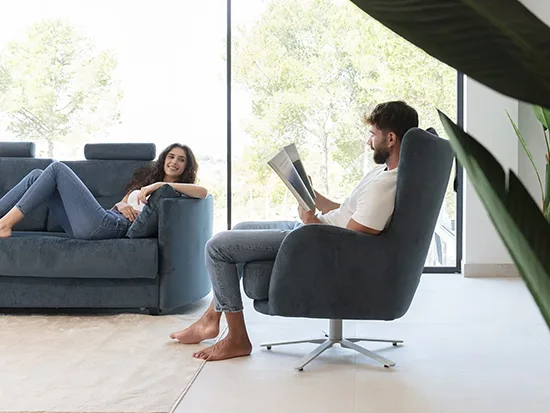 Fauteuil en tissu Fama Kylian bleu foncé avec une personne assise – Meubles Bouchiquet à Bergues (59)
