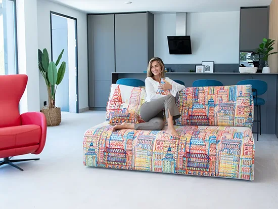 Canapé relax convertible Fama Indy avec une personne assise, présenté dans un salon – Meubles Bouchiquet à Bergues (59)