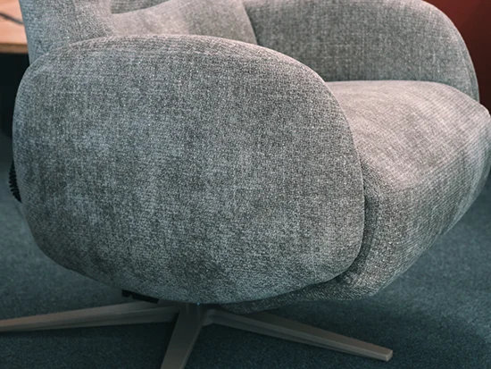 Détail de l’accoudoir arrondi du fauteuil relax gris en tissu